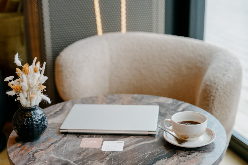 Espace de travail Plume&Muse avec ordinateur, café et cartes de visite