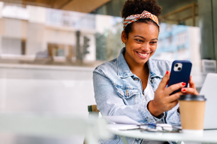 Jeune femme consultant LinkedIn sur son smartphone dans un café